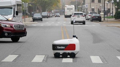 A food delivery robot crosses a street in Ann Arbor, Mich. on Thursday, Oct. 7, 2021. Robot food delivery is no longer the stuff of science fiction. Hundreds of little robots __ knee-high and able to hold around four large pizzas __ are now navigating college campuses and even some city sidewalks in the U.S., the U.K. and elsewhere.