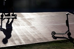 In this May 28, 2019, file photo a man on a scooter passes a parked scooter along the Mission Beach boardwalk in San Diego. San Diego is suing scooter companies to get them to pay the city's costs to defend any lawsuits generated by the two-wheeled vehicles that have proliferated on public sidewalks.