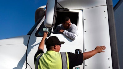 Senior instructor Markus Juarez, bottom, talks to student driver Jaime Rojas at California Truck Driving Academy in Inglewood, Calif., Wednesday, Nov. 17, 2021. Amid a shortage of commercial truck drivers across the U.S., a Southern California truck driving school sees an unprecedented increase in enrollment numbers. The increase is big enough that the school is starting an evening class to meet the demand, according to Tina Singh, owner and academy director of California Truck Driving Academy. 'I think that's only going to continue because there's a lot of job opportunities. We have over 100 active jobs on our job board right now,' said Singh. The companies that normally would not hire drivers straight out of school are '100 percent' willing to hire them due to shortage issues, the director added.