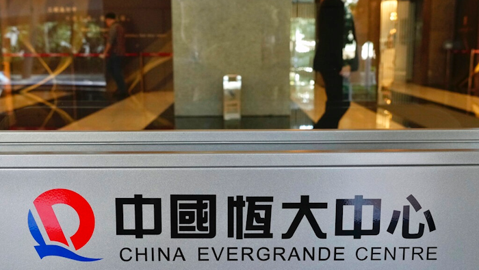 In this Oct. 4, 2021, file photo, a security guard stands at the headquarters of China Evergrande Group in Hong Kong. On Friday, Dec. 3, 2021, troubled Chinese developer China Evergrande Group, struggling under $310 billion in debt, warned it may run out of money to “perform its financial obligations,” sending regulators scrambling to reassure investors that China’s financial markets can be protected from a potential impact.