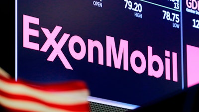 The logo for ExxonMobil appears above a trading post on the floor of the New York Stock Exchange, April 23, 2018. ExxonMobil says it is boosting its spending on greenhouse gas emission-reduction projects to $15 billion over the next six years and anticipates meeting its 2025 greenhouse gas emission-reduction plans by the end of this year.