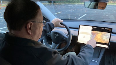 Vince Patton, a new Tesla owner, demonstrates on Wednesday, Dec. 8, 2021, on a closed course in Portland, Ore., how he can play video games on the vehicle's console while driving. Patton, of Portland, Ore., filed a complaint with federal regulators after discovering the feature in his new car.