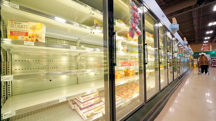A shopper walks past partially empty frozen food coolers at a grocery in Cranberry Township, Pa., on Jan. 11, 2022.