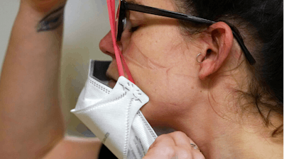 Registered nurse Jessalynn Dest pulls on a new N95 mask as indentations remain from another she had just removed after leaving a COVID-19 patient room in the acute care unit of Harborview Medical Center on Jan. 14, 2022, in Seattle.