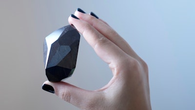 An employee of Sotheby's Dubai presents a 555.55 Carat Black Diamond 'The Enigma' to be auctioned at Sotheby's Dubai gallery, in Dubai, United Arab Emirates, Monday, Jan. 17, 2022.