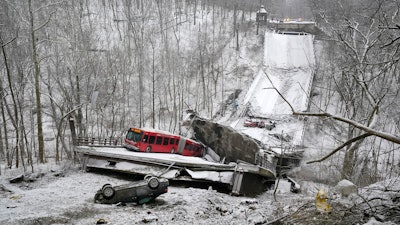 A Port Authority bus that was on a bridge when it collapsed Friday Jan. 28, 2022, is visible in Pittsburgh's East End. A two-lane bridge collapsed in Pittsburgh early Friday, prompting rescuers to rappel nearly 150 feet (46 meters) while others formed a human chain to help rescue multiple people from a dangling bus.