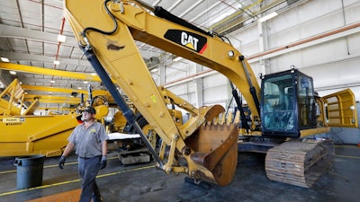 A Puckett Machinery Company technician walks past a new heavy duty Caterpillar excavator that awaits modification at Puckett Machinery Company in Flowood, Miss. Sept. 18, 2019. Caterpillar continued to see a healthy surge in sales during its fourth quarter of 2022, as the economy strengthens. Sales climbed 23% to $13.8 billion.