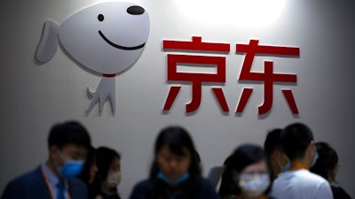 Visitors walk past a booth for Chinese online retailer JD.com at the China International Fair for Trade in Services (CIFTIS) in Beijing, Friday, Sept. 3, 2021. JD.com Inc., China’s biggest online retailer, and Canadian e-commerce service Shopify launched a venture Tuesday, Jan. 18, 2022, to give independent U.S. merchants access to JD.com’s 550 million customers.