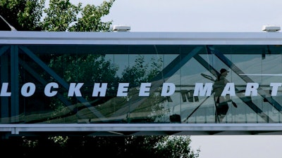 A man walks past a Lockheed Martin logo as he walks through a section of the company's chalet bridging a road at Farnborough International Airshow in Farnborough, southern England, Wednesday July 19, 2006. The Biden administration is suing to block a Lockheed Martin acquisition that it says would limit competition among companies that supply missiles to the Pentagon. The Federal Trade Commission said Tuesday, Jan. 25, 2022 that the $4.4 billion deal would eliminate the last independent U.S. supplier of key missile parts.