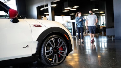 Customers move past a 2022 Clubman John Cooper Works model for sale on the floor of a Mini showroom Saturday, Aug. 21, 2021, in Highlands Ranch, Colo. Retail sales took an unexpected dip in December 2021 in what could be a signal that the increasing weight of persistently rising inflation is prompting a pullback in consumer spending.