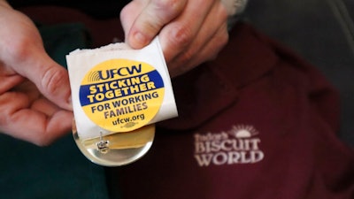 Former Tudor's Biscuit World employee Jennifer Patton hold stickers displaying the logo of the United Food & Commercial Workers Local 400 union at her coworker's home in Elkview, W.Va., on Jan. 20, 2022. Patton said she was retaliated against and fired by management after she joined efforts to unionize the restaurant. Employees at the Elkview, W.Va., restaurant have already case ballots to decide whether or not they want to create a union. The votes will be read Tuesday.