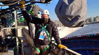 Associated Press photographer Chris Carlson poses for a photo while installing a remote camera on the roof of the National Stadium, known as the Bird's Nest, in Beijing on Jan. 28, 2022.