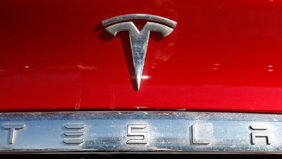 In this Feb. 2, 2020 file photo, the company logo sits on an unsold 2020 Model X at a Tesla dealership in Littleton, Colo. Tesla Inc. on Wednesday, Jan. 26, 2022 posted record fourth-quarter and full-year earnings as its deliveries soared despite a global shortage of computer chips that has slowed the entire auto industry. The Austin, Texas, company made $5.5 billion last year compared with the previous record year of $3.47 billion in net income posted in 2020. It was the electric vehicle and solar panel maker's third straight profitable year.