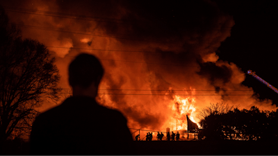 A bystander watches as Winston-Salem firefighters battle a structure fire at Weaver Fertilizer Co. on Monday, Jan. 31, 2022, in Winston-Salem, N.C.