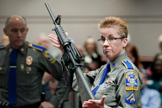Firearms training unit Detective Barbara J. Mattson, of the Connecticut State Police, holds up a Bushmaster AR-15 rifle, the same make and model of gun used by Adam Lanza in the December 2012 Sandy Hook School shooting, during a hearing of a legislative subcommittee in Hartford, Conn., Jan. 28, 2013.