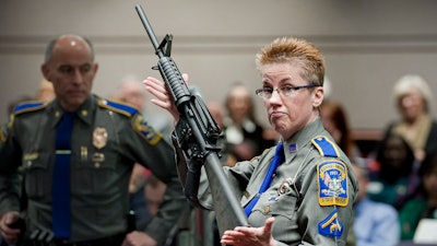 Firearms training unit Detective Barbara J. Mattson, of the Connecticut State Police, holds up a Bushmaster AR-15 rifle, the same make and model of gun used by Adam Lanza in the December 2012 Sandy Hook School shooting, during a hearing of a legislative subcommittee in Hartford, Conn., Jan. 28, 2013.