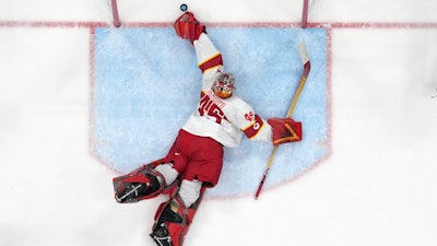 China goalkeeper Jieruimi Shimisi (Jeremy Smith) (45) reaches for a goal by United States' Brian O'Neill during a preliminary round men's hockey game at the 2022 Winter Olympics, Thursday, Feb. 10, 2022, in Beijing.