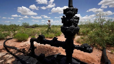 Ashley Williams Watt walks near a wellhead and flowline at her ranch, Friday, July 9, 2021, near Crane, Texas. The wells on Watt's property seem to be unplugging themselves. Some are leaking dangerous chemicals into the ground, which are seeping into her cattle's drinking water. And she doesn't know how long it's been going on.