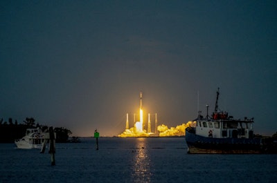 A SpaceX Falcon 9 rocket launches from Florida. The image shows the rocket clearing the lightning arrestor towers at dusk.