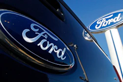 This Oct. 25, 2011 file photo shows a Ford logo on the tailgate of a pick-up truck, and on a Ford dealership sign in Salem, N.H. Ford Motor Co. reversed a loss and rode some big accounting changes to post a $17.94 billion net profit last year, even as it battled computer chip shortages that caused factory slowdowns and vehicle shortages.
