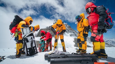 Mariusz Potocki and Sherpa team drilling the highest ice core ever recovered at 8020m elevation with the summit of Mount Everest in the background.