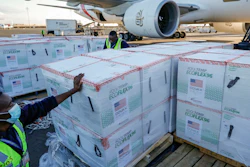 An airport worker stands next to boxes of Moderna coronavirus vaccines donated by the U.S. government, Nairobi, Kenya, Aug. 23, 2021.