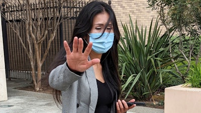 Julie Lee Choi waves off reporters outside Santa Clara Superior Court in San Jose, Calif., on Tuesday, March 29, 2022. Choi, accused of harassing Apple CEO Tim Cook with pleas for sex and other crude suggestions before showing up at his Silicon Valley home last autumn and suggesting she could become violent agreed to stay way from him for the next three years under an agreement approved Tuesday.