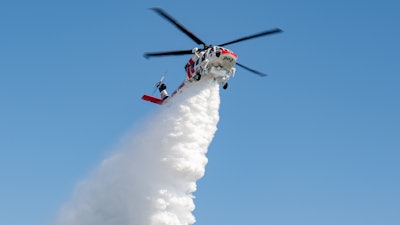 A Firehawk aircraft operated by CAL FIRE demonstrates the powerful concentration of water released from its 1,000 gallon tank for effective wildfire fighting.