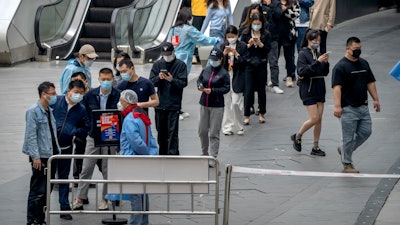 People line up for COVID-19 tests at a testing site in an office complex in Beijing, Friday, April 29, 2022.