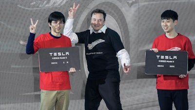 In this photo released by China's Xinhua News Agency, Tesla CEO Elon Musk, center, poses with Tesla owners at a delivery ceremony for the first Tesla Model 3 cars made at Tesla's Shanghai factory in Shanghai on Jan. 7, 2020. Musk’s ties to China through his role as electric car brand Tesla’s biggest shareholder could add complexity to his bid to buy Twitter.