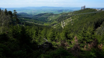 Visitors cross a suspension bridge for the pedestrians that is the longest such construction in the world shortly after its official opening at a mountain resort in Dolni Morava, Czech Republic, Friday, May 13, 2022. The 721-meter (2,365 feet) long bridge is built at the altitude of more than 1,100 meters above the sea level. It connects two ridges of the mountains up to 95 meters above a valley between them.