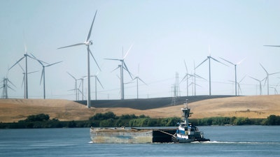 A tugboat pushes a barge down the Sacramento River past wind turbines near Rio Vista, Calif., on Monday, Sept. 23, 2013.