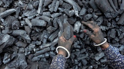 A woman works at a coal depot in Ahmedabad, India, Monday, May 2, 2022. An unusually early and brutal heat wave is scorching parts of India, where acute power shortages are affecting millions as demand for electricity surges to record levels. Supplies of coal at many thermal power plants are running perilously low, spawning daily power outages in several states. The shortages are sparking scrutiny of India’s long reliance on coal, which produces 70% of the country’s electricity.