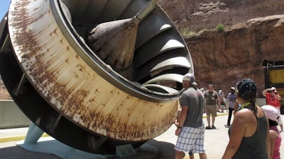 Tourists look at an old turbine that was replaced at the Glen Canyon Dam.
