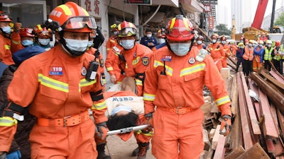In this photo released by Xinhua News Agency, rescuers evacuate a woman pulled alive from a collapsed building in Changsha, central China's Hunan Province, May 1, 2022. The woman was rescued Sunday from the rubble of a building in central China more than 50 hours after it collapsed, leaving dozens trapped or missing, state media said.