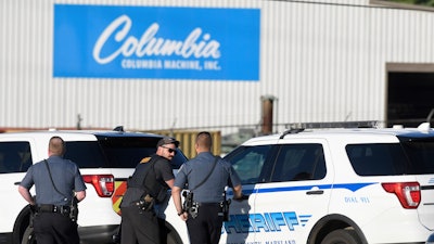 Police stand near where a man opened fire at a business, killing three people before the suspect and a state trooper were wounded in a shootout, according to authorities, in Smithsburg, Md., Thursday, June 9, 2022. The Washington County (Md.) Sheriff's Office said in a news release that three victims were found dead at Columbia Machine Inc. and a fourth victim was critically injured.