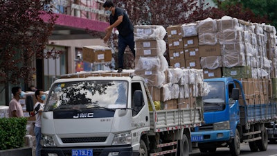 Workers load boxes of goods from a truck outside a wholesale clothing mall in Beijing on Tuesday, June 14, 2022. China's factory output rebounded in May, adding to a recovery from the latest COVID-induced economic slump after controls that shut down Shanghai and other industrial centers eased.
