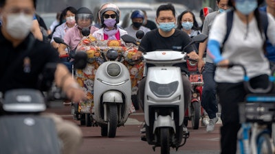 Commuters wearing face masks ride across an intersection in the central business district in Beijing, Friday, June 17, 2022.