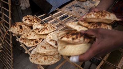 A worker collects Egyptian traditional 'baladi' flatbread at a bakery in the el-Sharabia, Shubra district, Cairo, March 2, 2022.