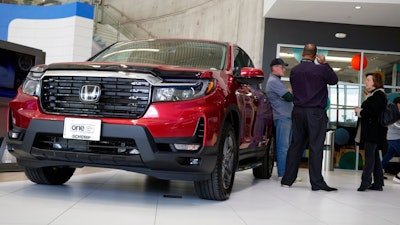 Customers confer with a salesperson as a 2022 Ridgeline pickup truck sits on the showroom floor of a Honda dealership, Friday, April 15, 2022, in Highlands Ranch, Colo.