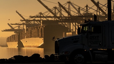 A truck arrives to pick up a shipping container near vessels moored at Maersk APM Terminals Pacific at the Port of Los Angeles, Nov. 30, 2021.