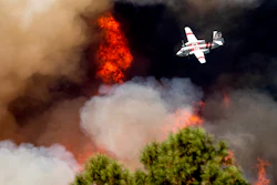 An air tanker flies past flames while battling the Oak Fire in Mariposa County, Calif., Sunday, July 24, 2022. Wildfires, floods and soaring temperatures have made climate change real to many Americans. Yet a sizeable number continue to dismiss the scientific consensus that human activity is to blame. That's in part because of a decades-long campaign by fossil fuel companies to muddy the facts and promote fringe explanations.