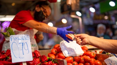 A customer pays for vegetables at the Maravillas market in Madrid, on May 12, 2022. Inflation figures for Europe will be released Friday, July 1, 2022, as Russia's war in Ukraine has worsened the worldwide surge in consumer prices. For months, inflation in the 19 countries that use the euro has risen at the fastest pace since record-keeping for the currency began.