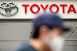 A man walks past a Toyota dealer in Tokyo on May 11, 2022. Toyota Motor Corp. reported Thursday, Aug. 4, 2022 a quarterly profit of 736.8 billion yen ($5.5 billion), down from 897.8 billion yen the previous year.
