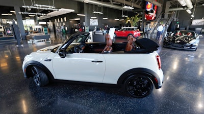 A sales associate talks with a prospective buyer of a Cooper SE electric vehicle on the showroom floor of a Mini dealership July 7, 2022, in Highlands Ranch, Colo. The surprise deal by Senate Democrats on a pared-down bill to support families, boost infrastructure and fight climate change is likely to jump start sales of electric vehicles.