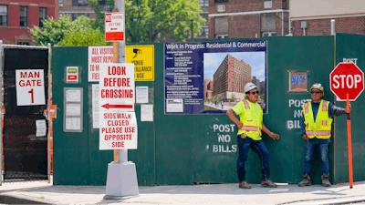 Construction workers help direct traffic outside a residential and commercial building under construction at the Essex Crossing development on the Lower East Side of Manhattan, Thursday, Aug. 4, 2022. America’s hiring boom continued last month as employers added a surprising 528,000 jobs despite raging inflation and rising anxiety about a recession.