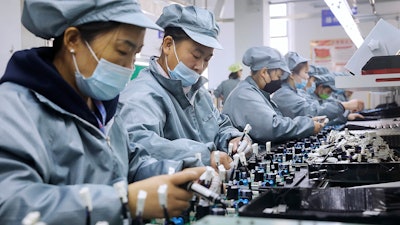 Workers wearing face masks assemble electronic parts at a factory in Huaibei in central China's Anhui Province on Nov. 29, 2021. Chinese manufacturing contracted in August 2022 amid weak export and consumer demand, a survey showed Wednesday, Aug. 31, 2022, adding to downward pressure on the struggling economy.