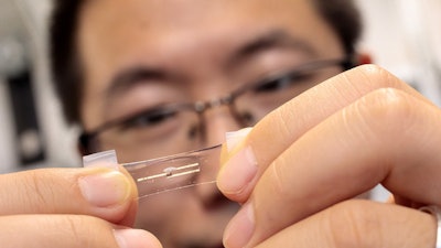 The wearable neuromorphic chip, made of stretchy semiconductors, can implement artificial intelligence (AI) to process massive amounts of health information in real time. Above, Asst. Prof. Sihong Wang shows a single neuromorphic device with three electrodes.