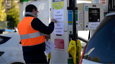 A man tapes posters reading 'Only diesel remains' in a gas station in Paris, Tuesday, Oct.11, 2022.
