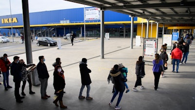 People wearing protective face mask line up in a queue outside the Swedish furniture giant Ikea shop the last day of the opening of non-essential shops during the coronavirus disease (COVID-19) outbreak, in Aubonne, Switzerland, Saturday, January 16, 2021.